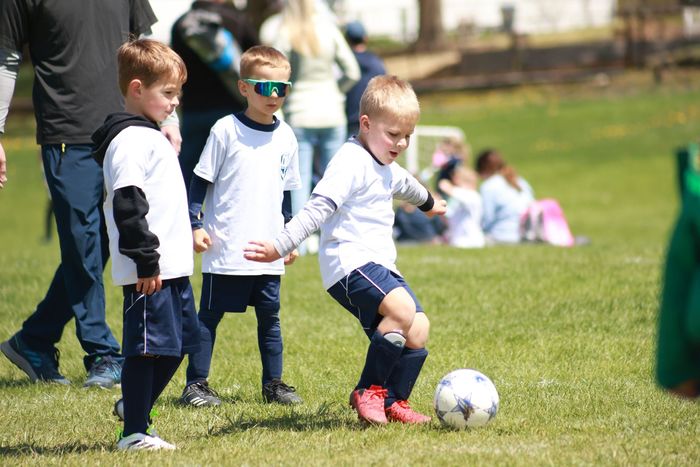 Three boys in white jerseys playing soccer