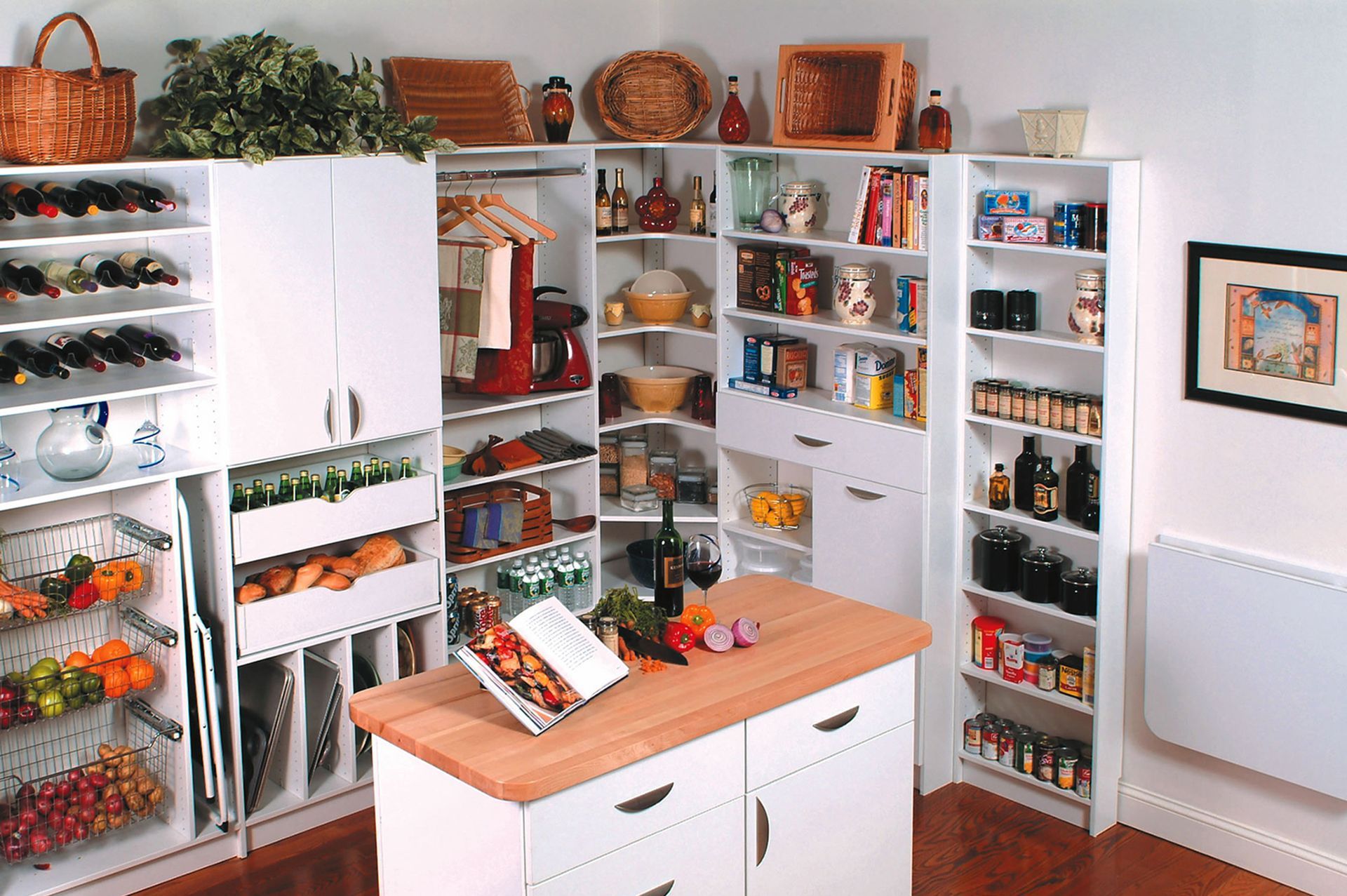White kitchen cabinets with shelves, storing food items, wine bottles, and a red mixer, next to a wood-topped island.