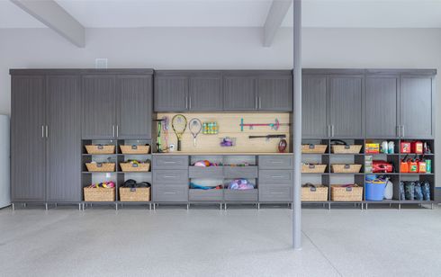 Gray garage cabinets with storage baskets and pegboard; against a light gray wall.