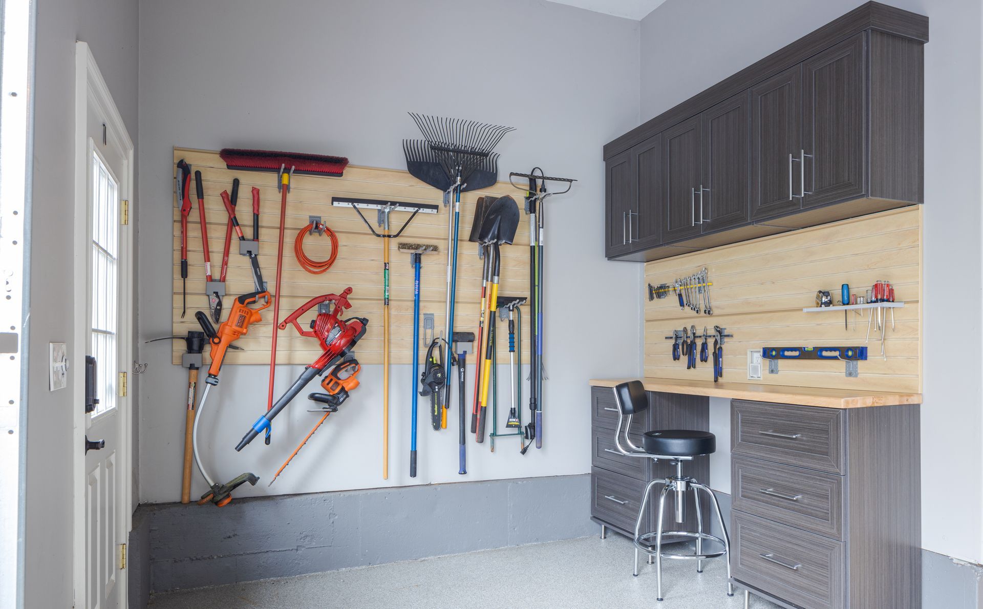 Garage interior with tools organized on pegboards, cabinets, and a workbench.