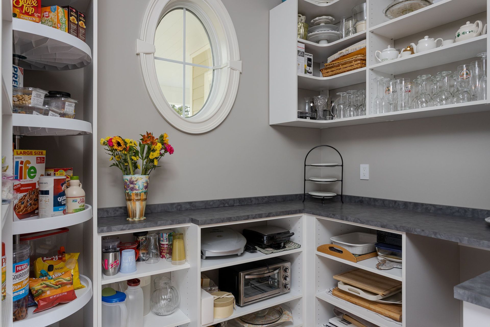 Walk-in closet with wooden shelves, clothes, luggage, and shoes.
