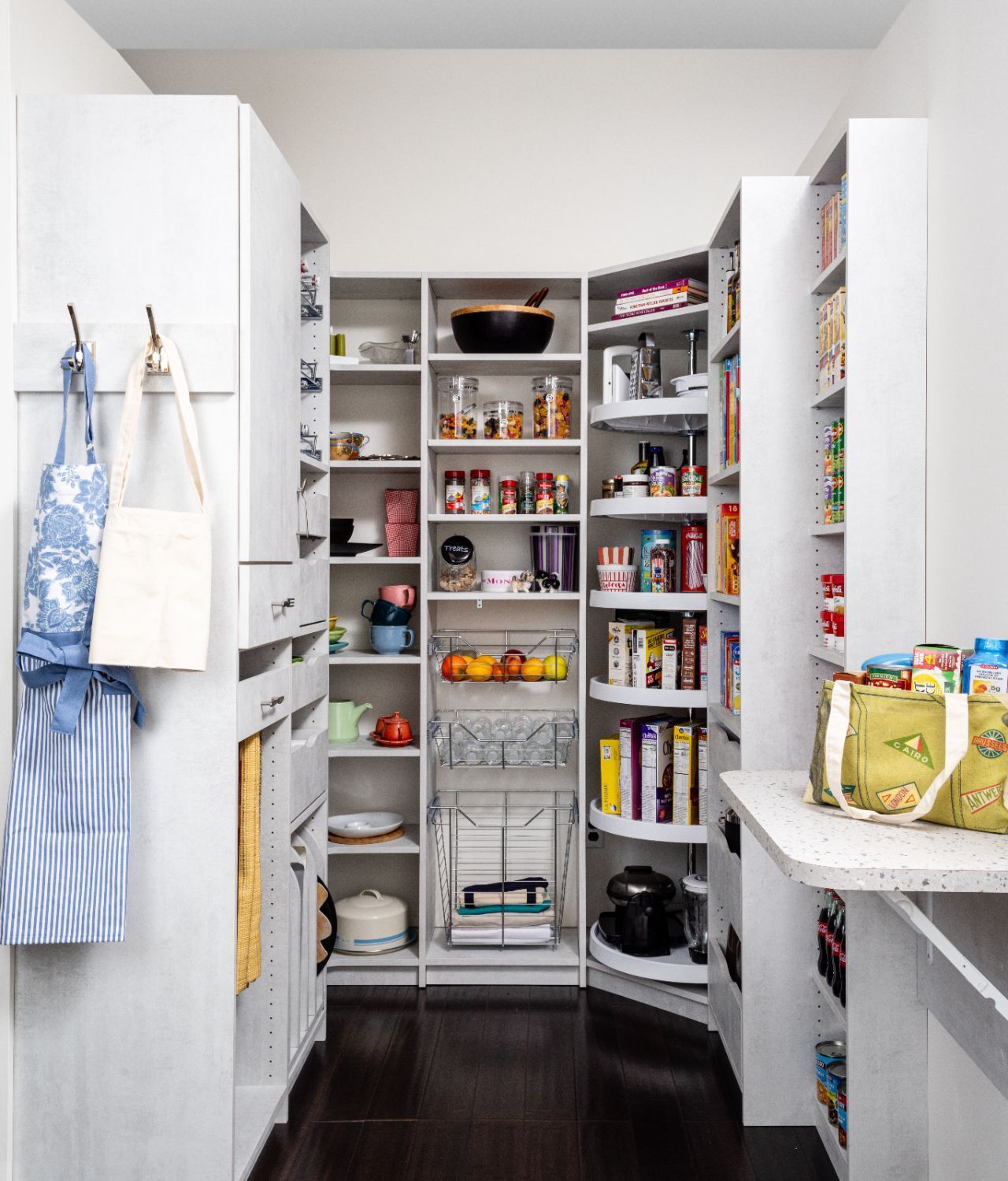 White kitchen cabinets with shelves, storing food items, wine bottles, and a red mixer, next to a wood-topped island.