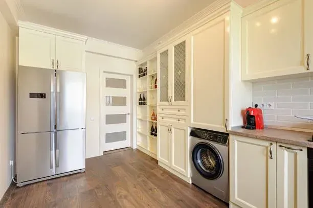 Kitchen interior featuring stainless steel appliances, white cabinetry, a washing machine, and an open wine rack.