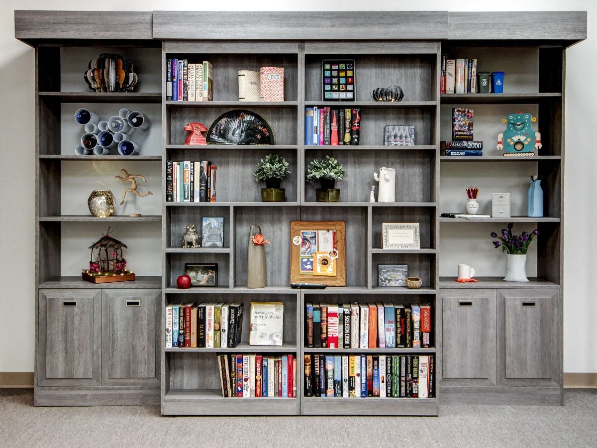 Modern laundry room with stacked washer/dryer, stainless steel cabinets, and blue accents.