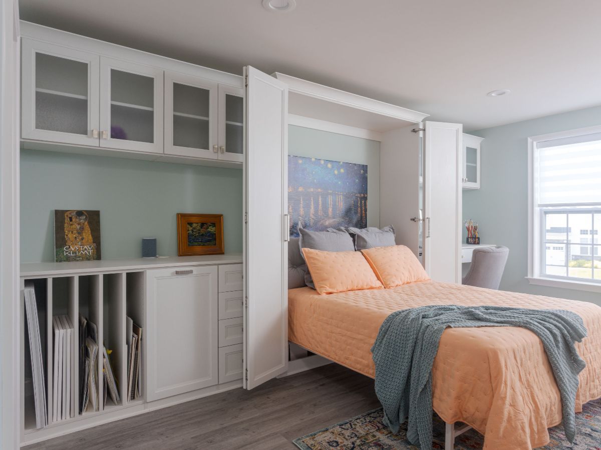 White kitchen cabinets with shelves, storing food items, wine bottles, and a red mixer, next to a wood-topped island.