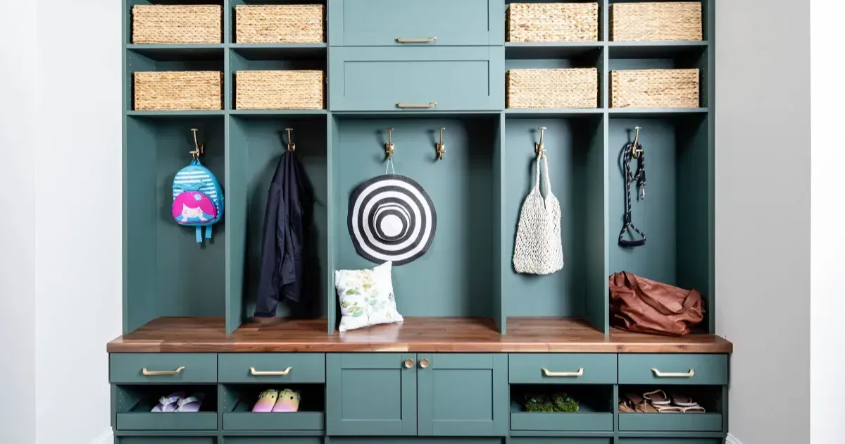Spacious white walk-in closet with island, clothing racks, and full-length mirror. Wooden floor, two chandeliers.
