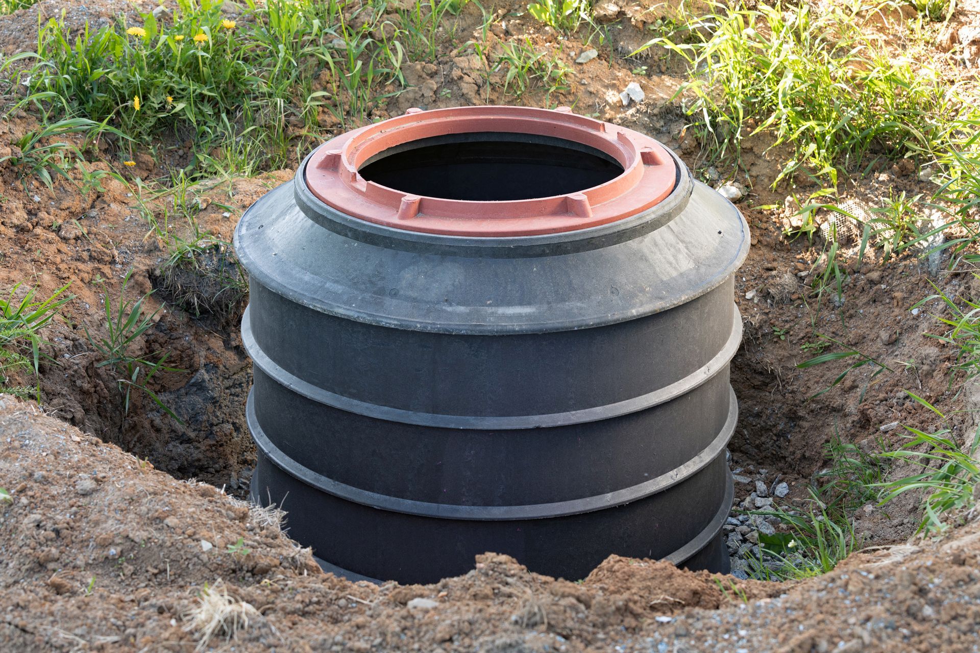 a large black barrel is sitting in a hole in the ground .