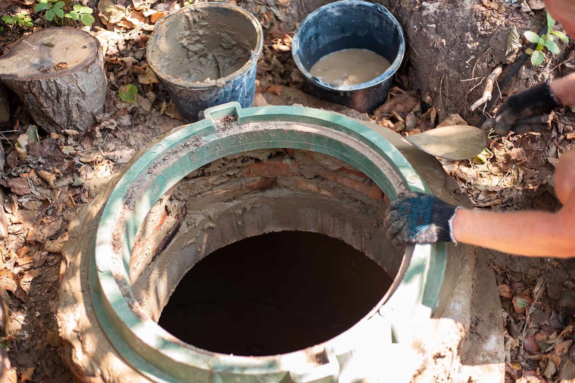 a man is working on a manhole cover with a shovel and buckets of cement