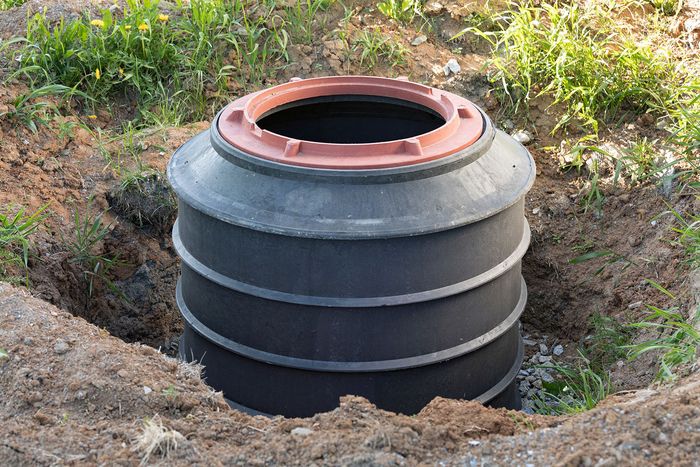 a large black barrel is sitting in a hole in the ground .