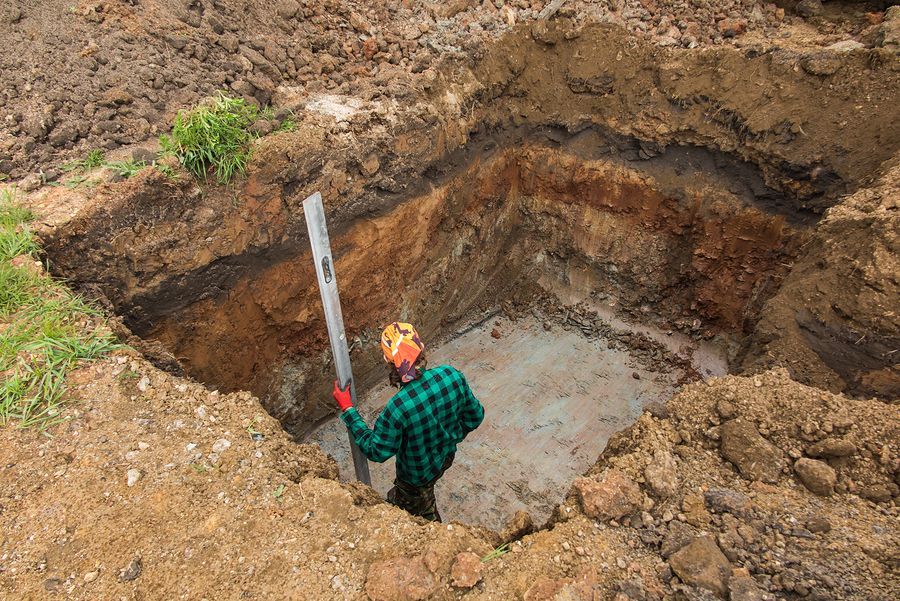 a man is standing in a hole in the dirt holding a level