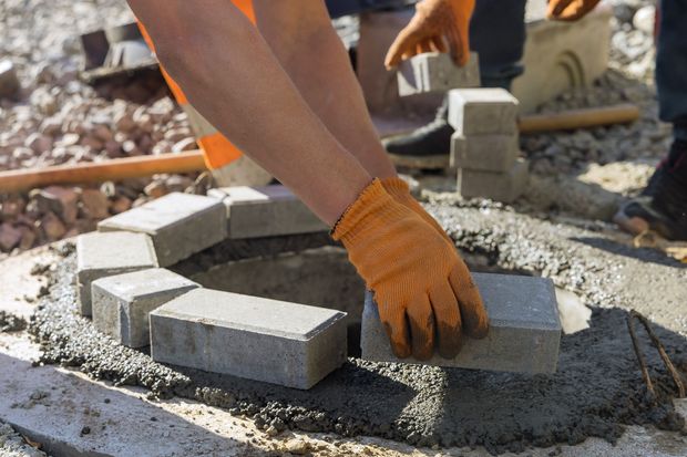 a man wearing orange gloves is laying bricks in a hole