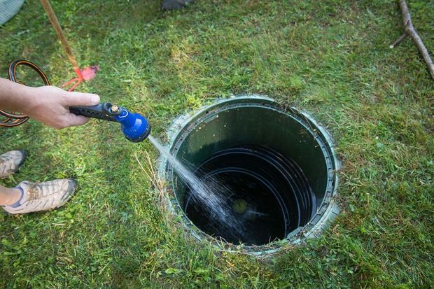 a person is cleaning a septic tank with a hose
