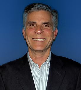 A man in a suit and striped shirt is smiling for the camera