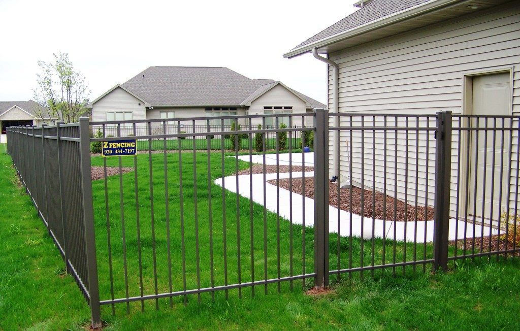 An aluminum fence surrounds a lush green yard 
