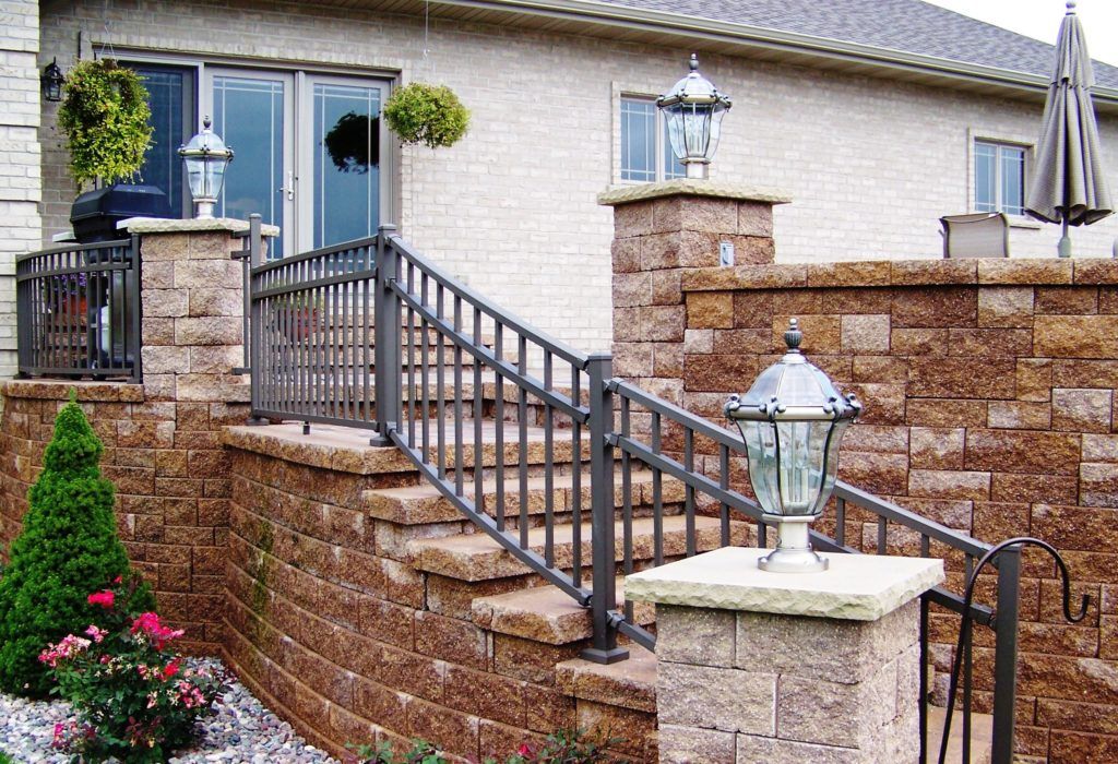 A brick wall with stairs and an aluminum railing leading up to a house