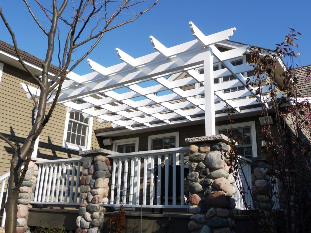 A house with a white pergola on top of a deck