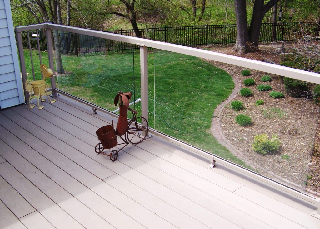 A rocking horse is sitting on a deck next to a glass railing.