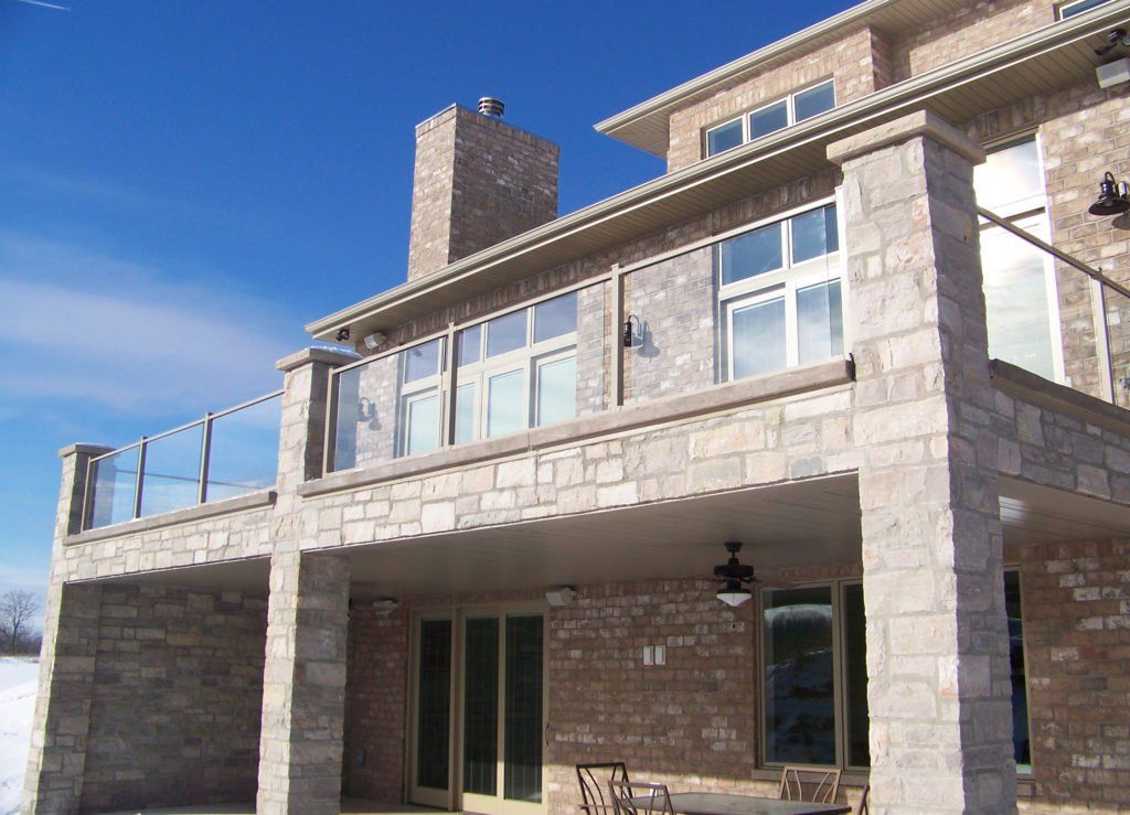 A large brick house with a large balcony and glass railing