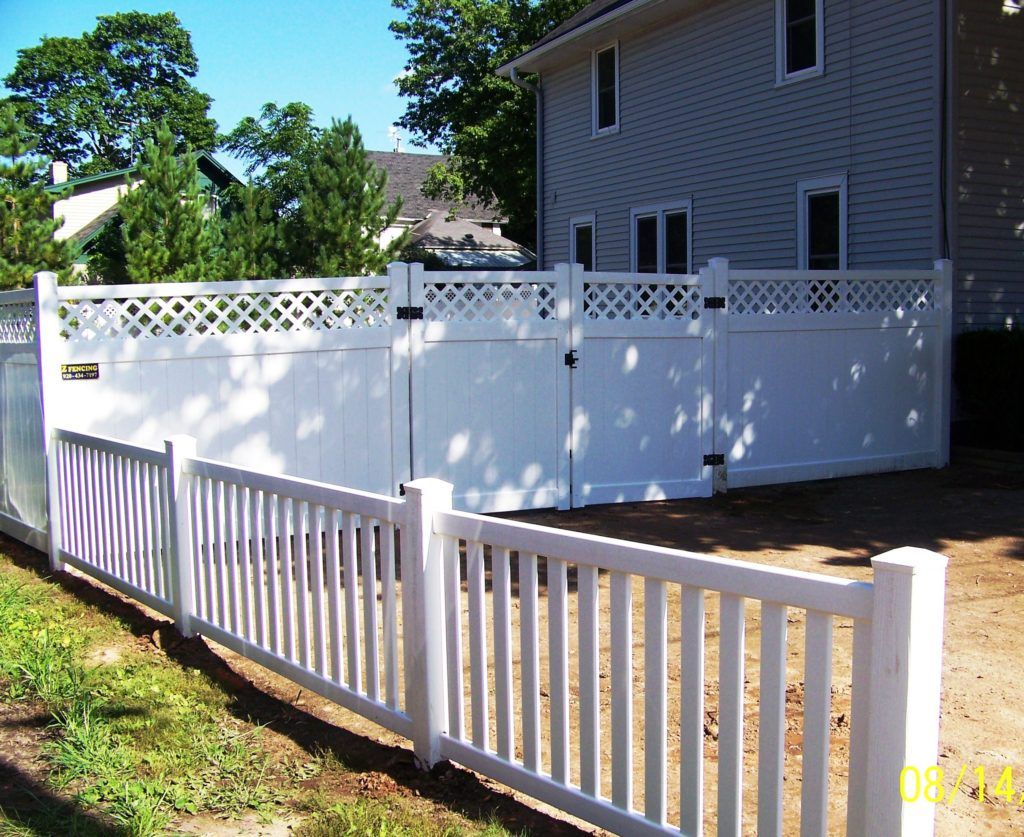 A white  vinyl fence with a gate in front of a house