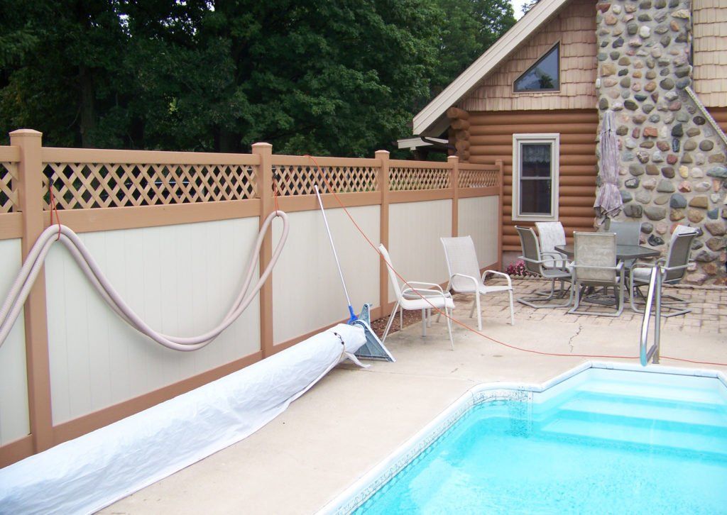 A fence with a lattice top surrounds a swimming pool 