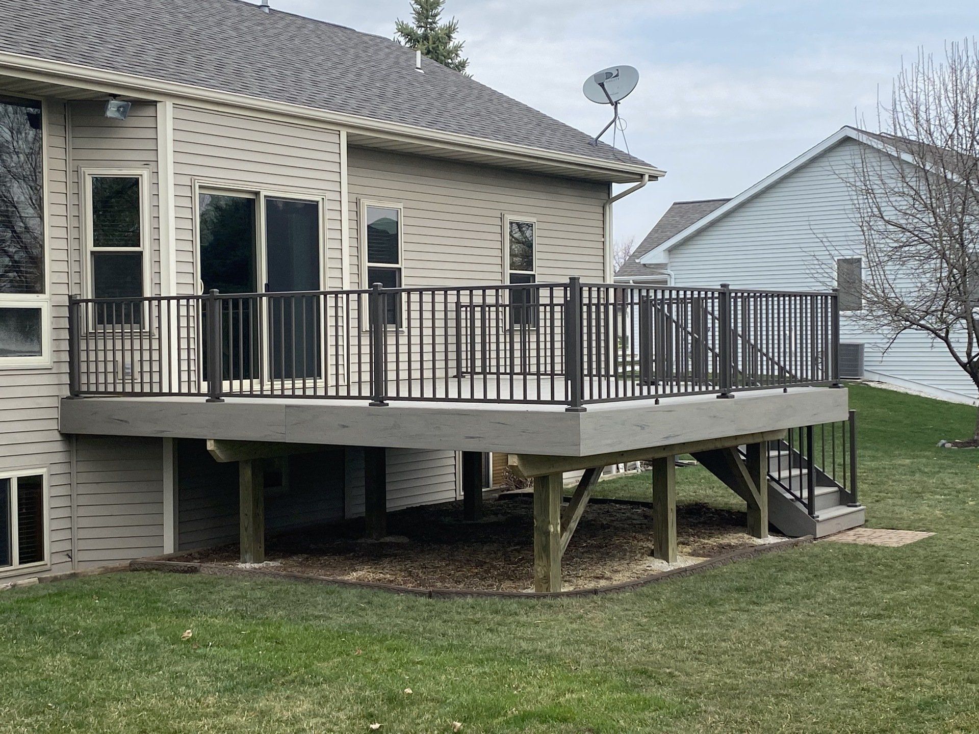 A large deck with stairs is in the backyard of a house.