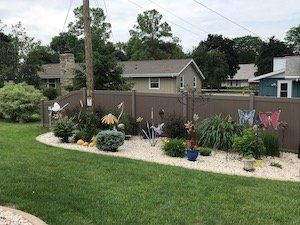 A backyard with a vinyl fence and lots of plants and flowers.