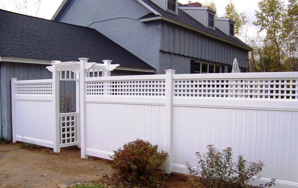 A white fence with an arbor in the middle of the fence