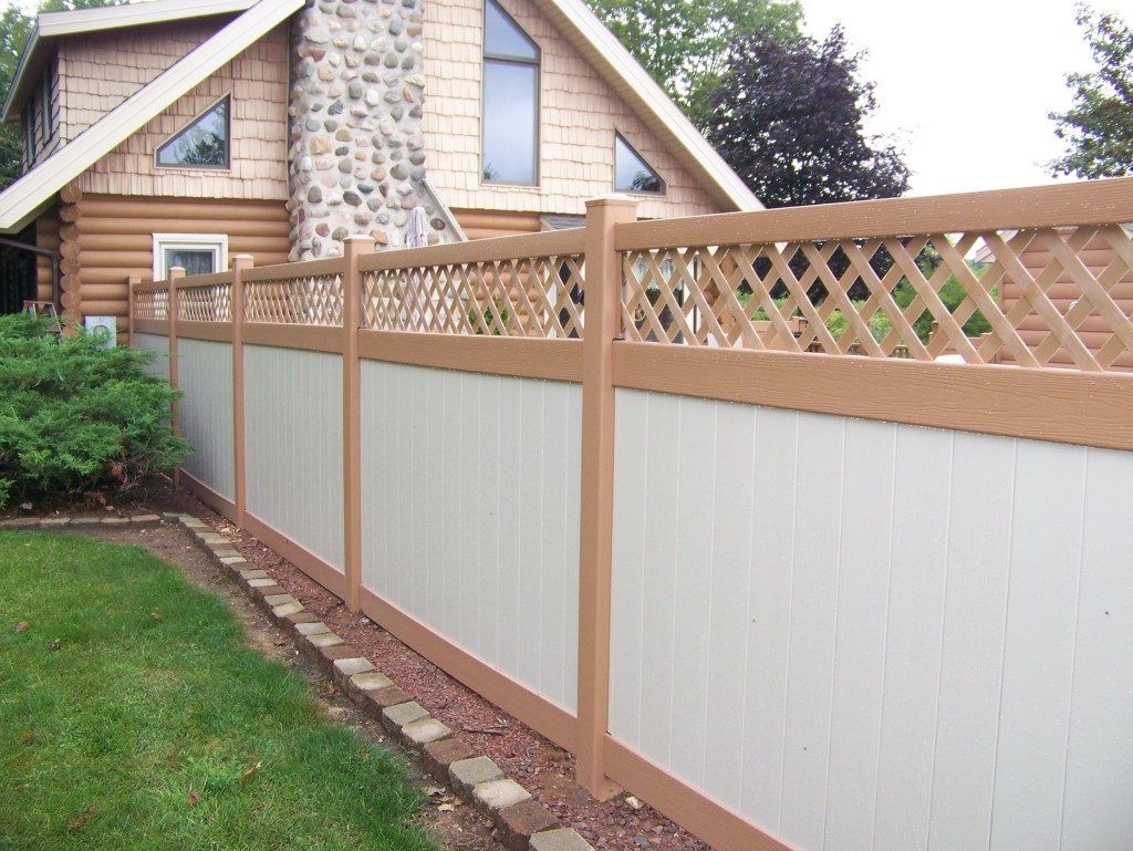 A white and brown fence with a lattice top 