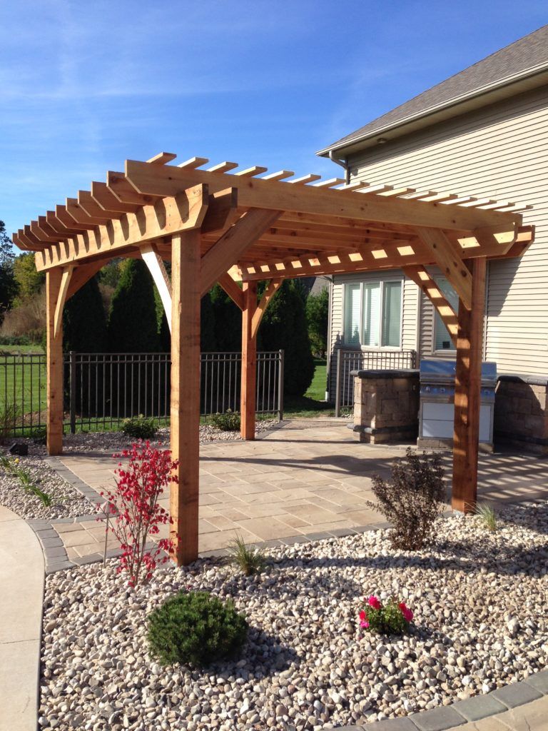 A wooden pergola is sitting on the patio of a house