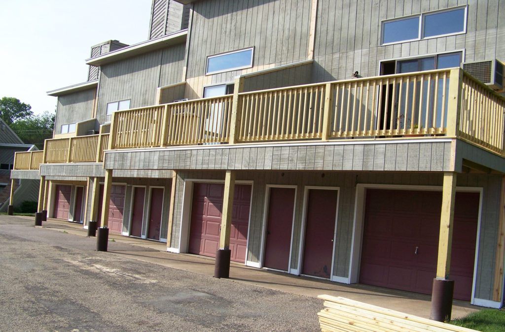A row of garages with a balcony and wooden railing