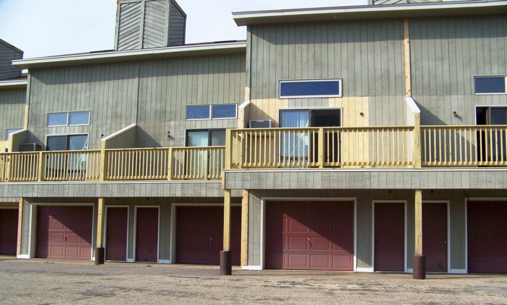 A row of garages with a balcony and wooden railing