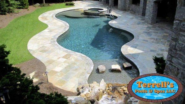 A large swimming pool is surrounded by a stone walkway and a sign that says terrell 's pool & spa
