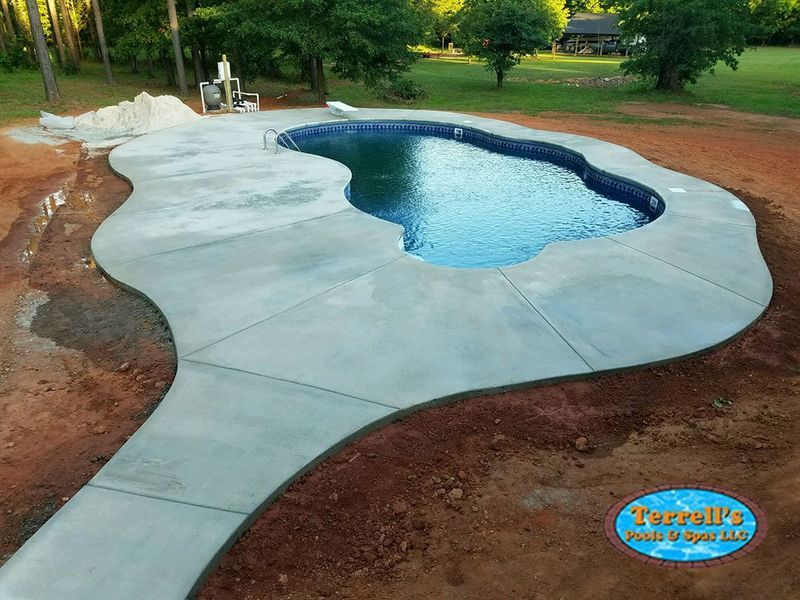 A large swimming pool with a concrete walkway around it