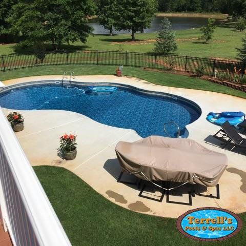 A large swimming pool is surrounded by a fence and lawn.