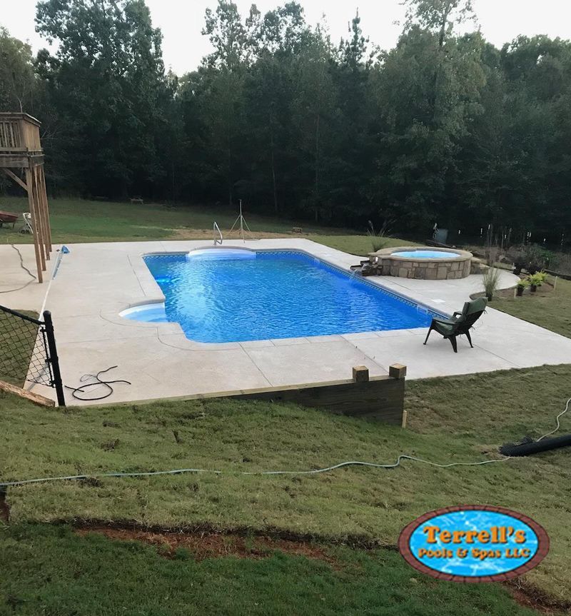 A large swimming pool surrounded by grass and trees with a terrall 's logo in the corner