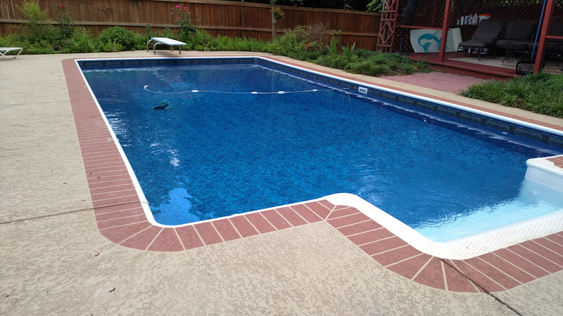 A large blue swimming pool with a brick border