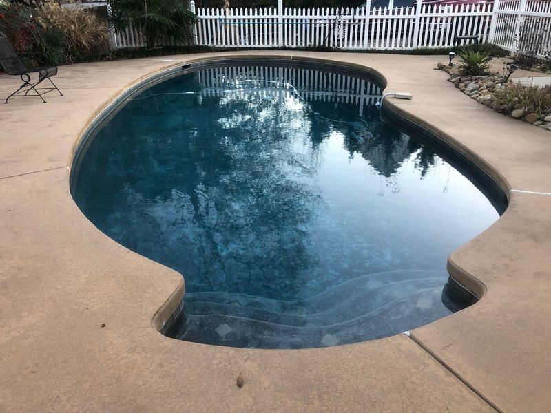 A large swimming pool with a white picket fence surrounding it