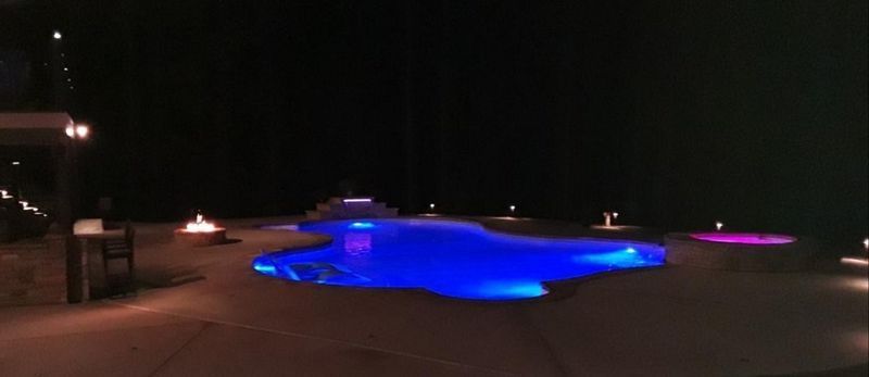 A large swimming pool is lit up at night.