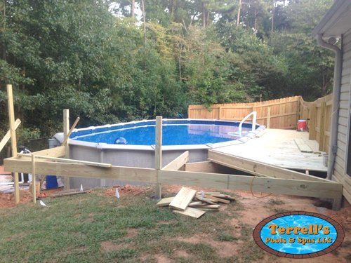 A large swimming pool is being built next to a wooden deck.