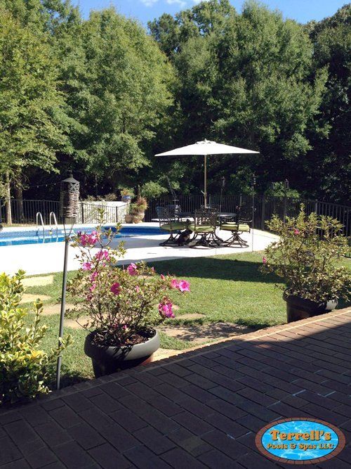 A large swimming pool with a white umbrella in the backyard