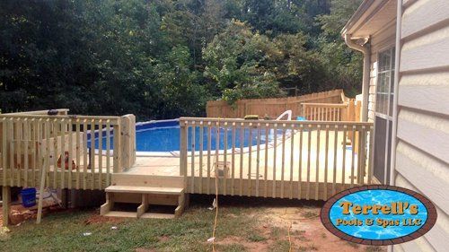 A wooden deck with a swimming pool in the background