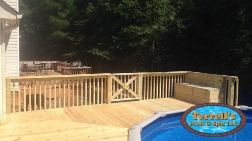 A wooden deck next to a pool with a sign that says terrell 's pool & spa