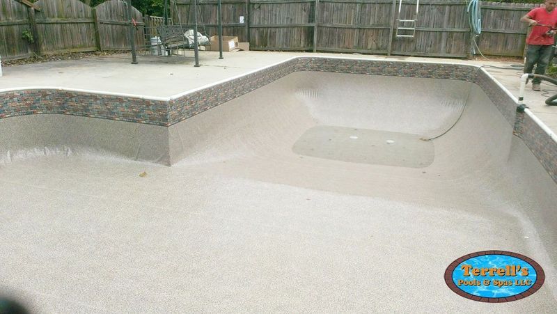 A man is standing next to a swimming pool that is being remodeled.