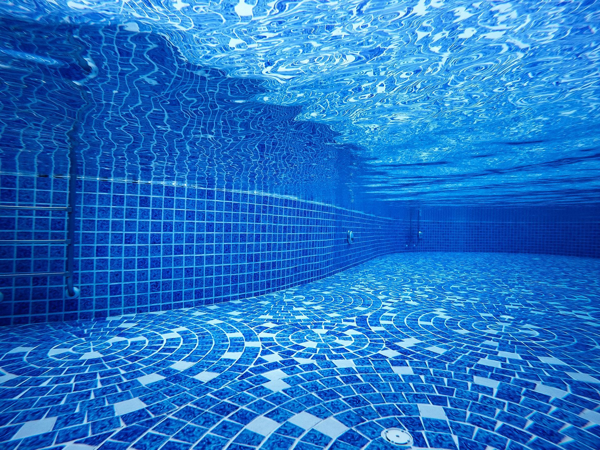 A underwater view of a swimming pool with blue tiles.