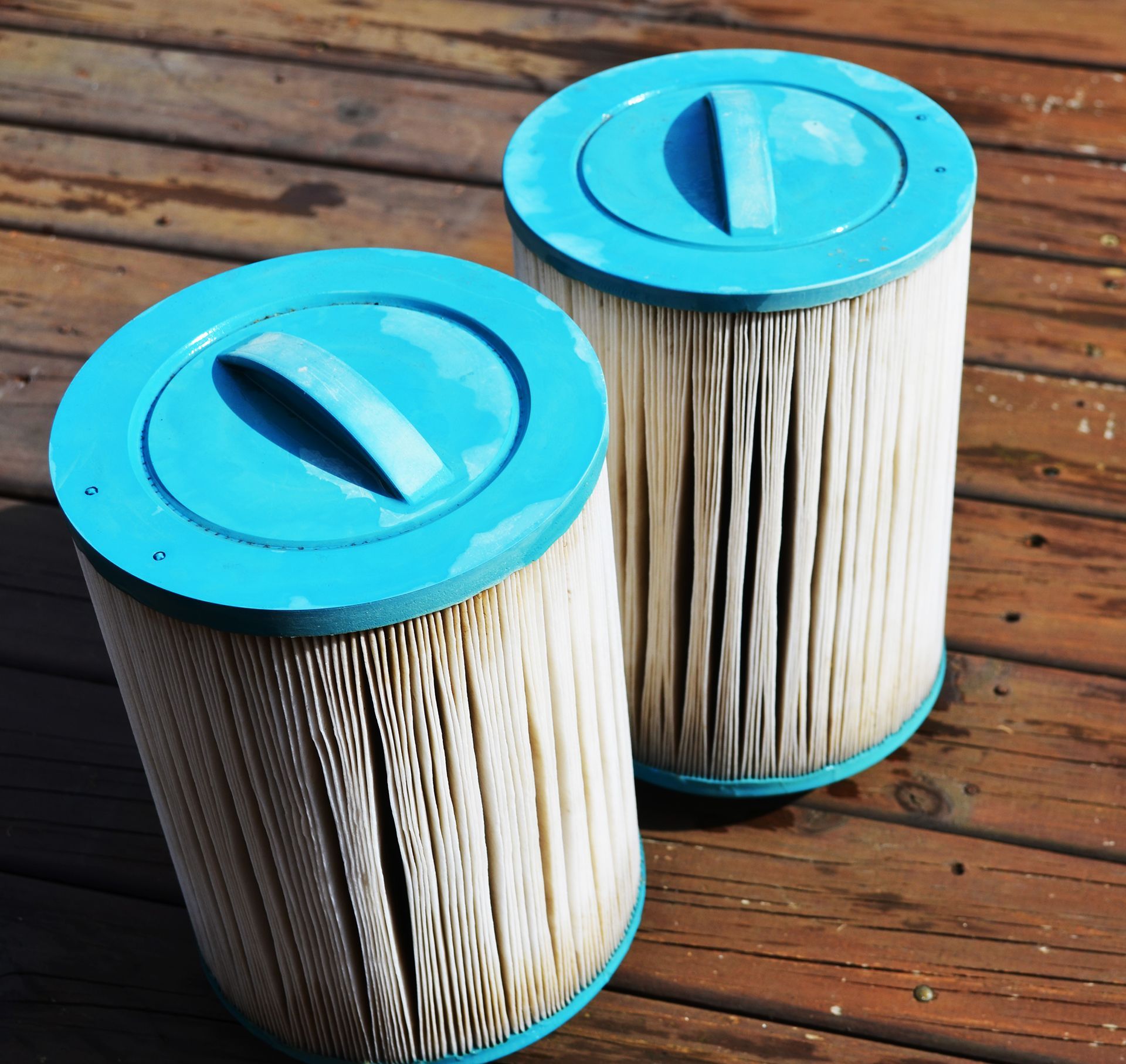 Two filter cartridges with blue lids are sitting on a wooden deck