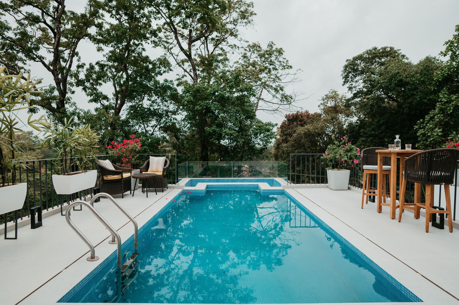 A large swimming pool is surrounded by chairs and tables.