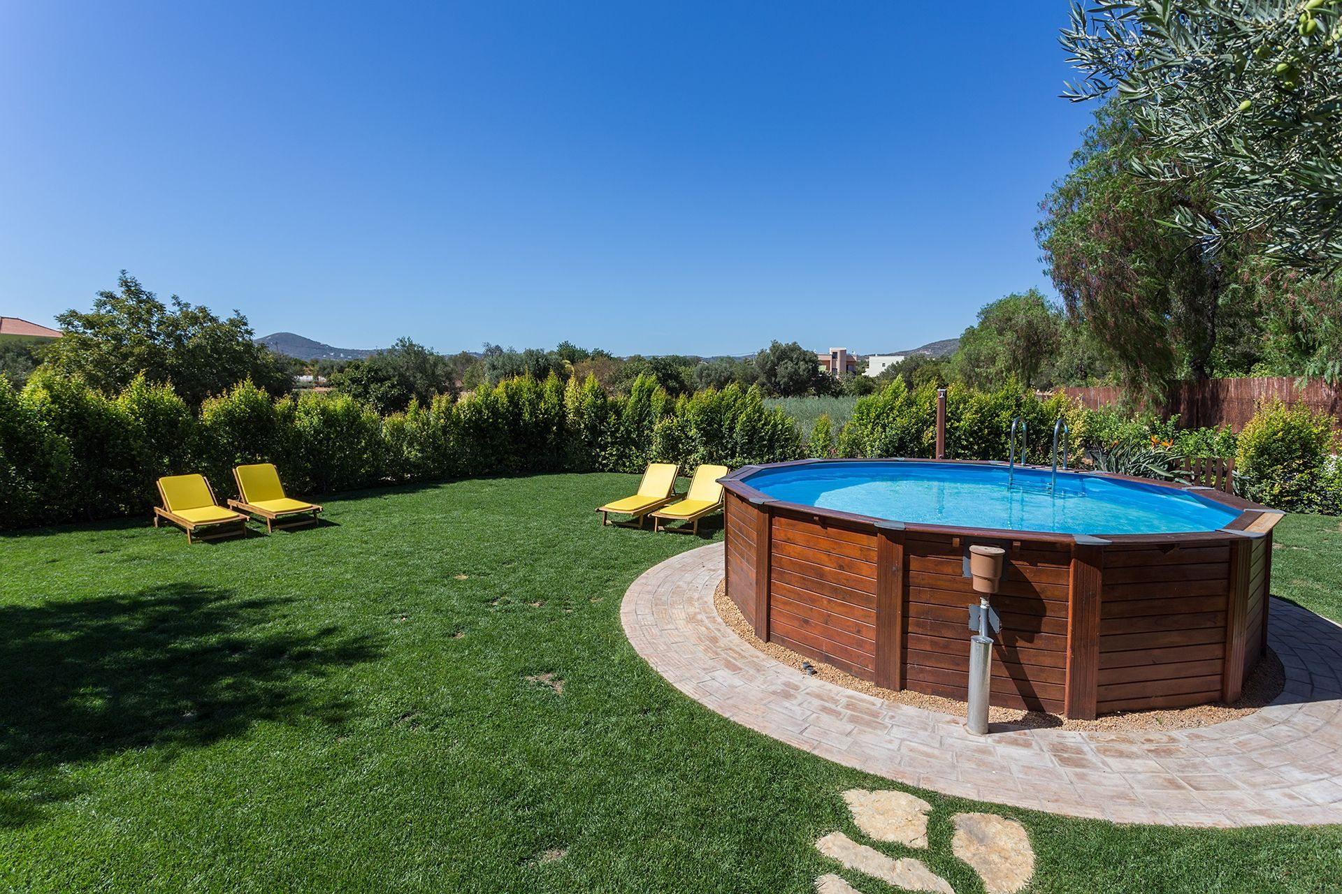 A large swimming pool is in the middle of a lush green yard.