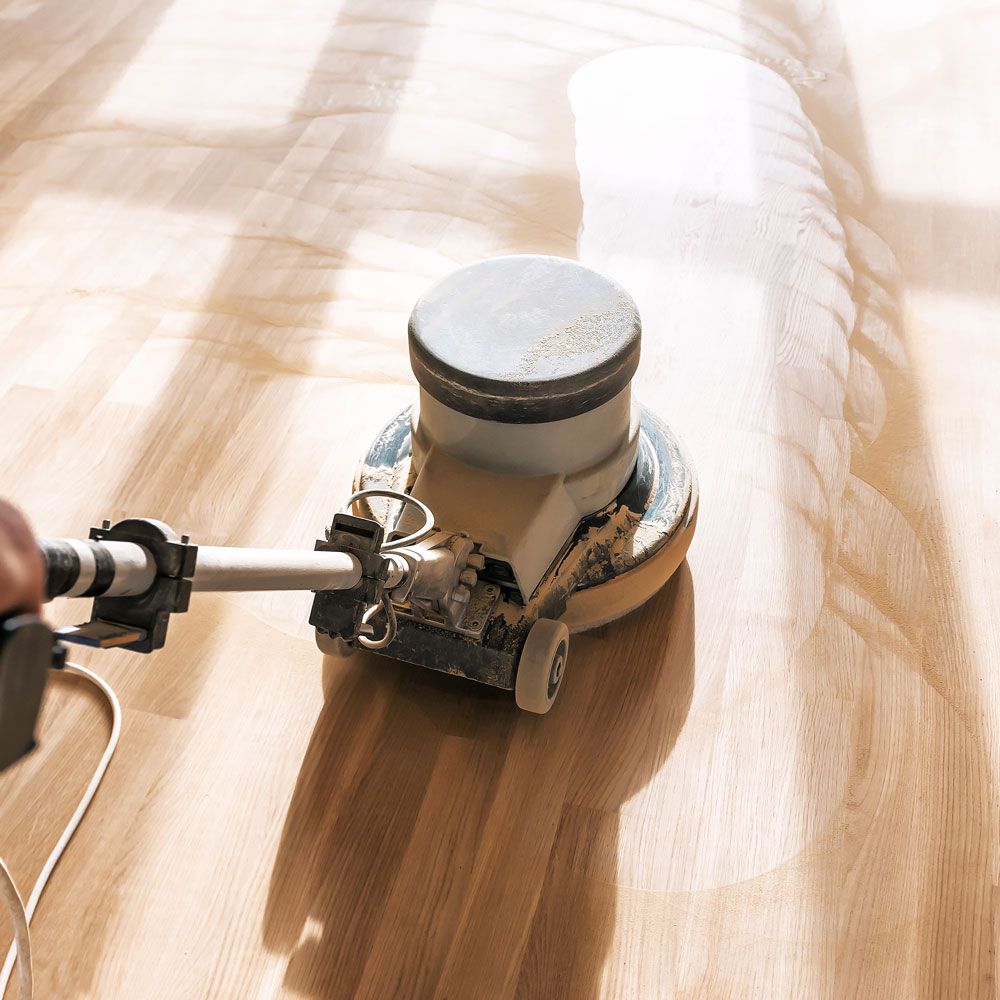 A person is using a machine to polish a wooden floor.