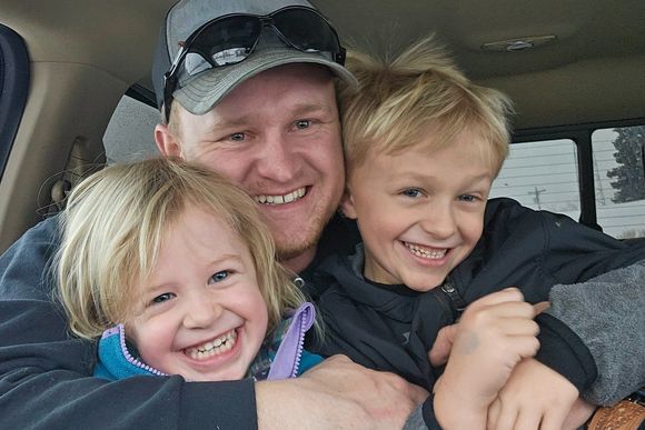 A man is hugging two children in a car.