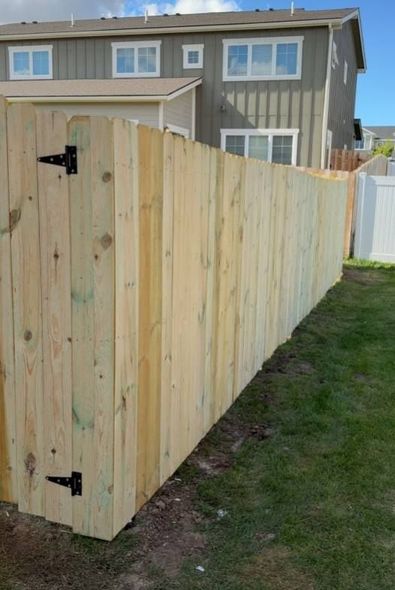 A wooden fence is in the backyard of a house.